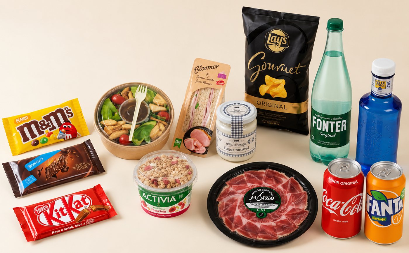 Surtido de una SmartShop: chocolatinas, un bol de ensalada, un yogur con frutos rojos, un sándwich de jamón y queso, un tarro de yogur natural, jamón serrano, patatas fritas, dos aguas embotelladas y dos refrescos.
